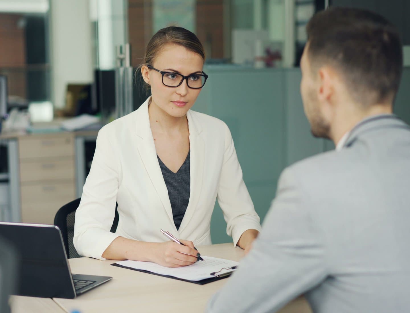 A consultant taking notes during a one-to-one meeting with a candidate